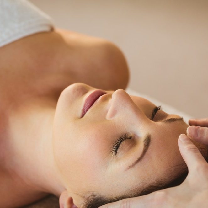 young-woman-having-a-reiki-treatment-in-therapy-ro-P2C2U5N